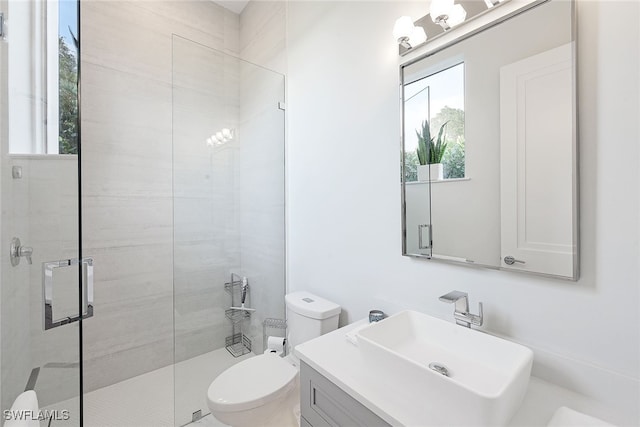 bathroom with a tile shower, vanity, and toilet