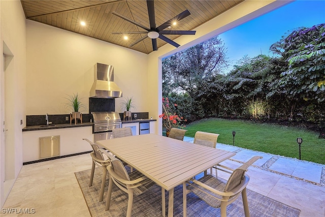 patio terrace at dusk featuring ceiling fan, area for grilling, a yard, and sink