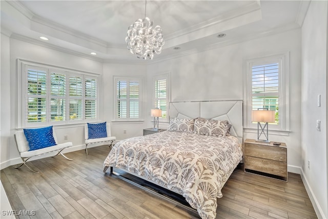 bedroom featuring a raised ceiling, wood-type flooring, ornamental molding, and a chandelier