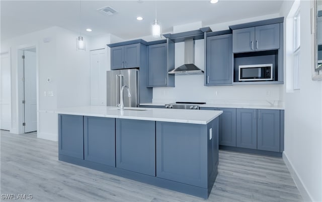 kitchen featuring pendant lighting, wall chimney exhaust hood, stainless steel appliances, and light hardwood / wood-style flooring