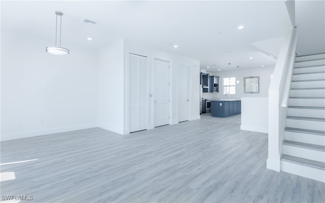 unfurnished living room featuring sink and hardwood / wood-style flooring