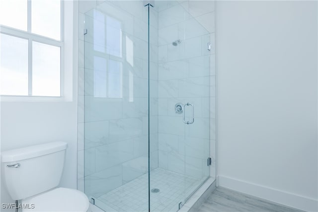 bathroom with toilet, an enclosed shower, and hardwood / wood-style flooring