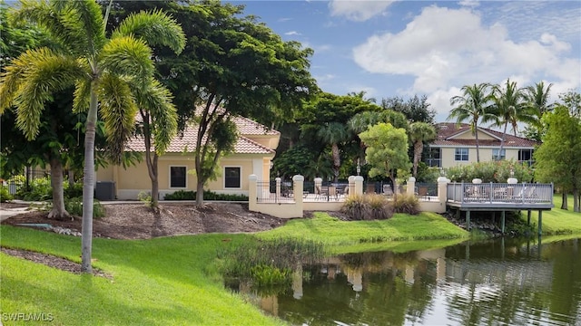 exterior space featuring a deck with water view and a lawn