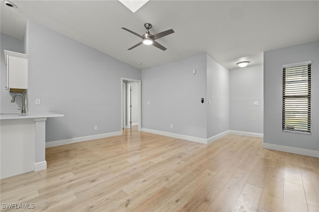 unfurnished living room with ceiling fan, light hardwood / wood-style flooring, and sink