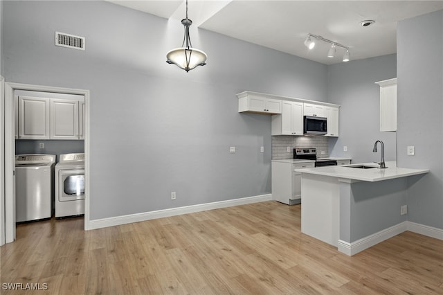 kitchen featuring white cabinets, pendant lighting, and independent washer and dryer