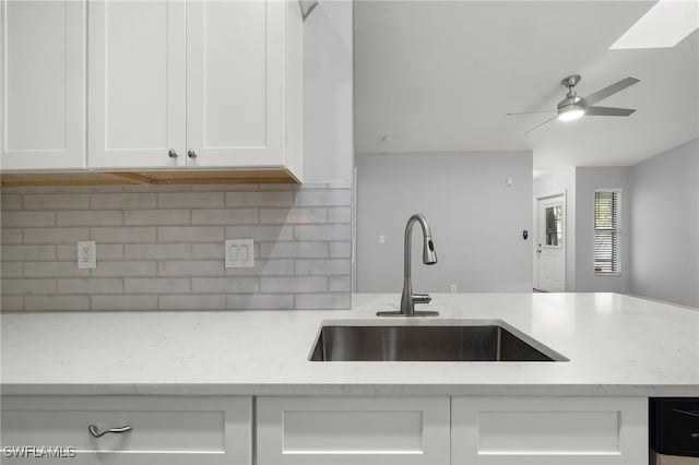 kitchen featuring white cabinetry, light stone counters, tasteful backsplash, and sink