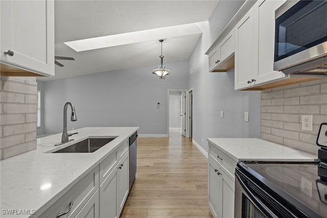 kitchen featuring sink, white cabinetry, stainless steel appliances, and a skylight