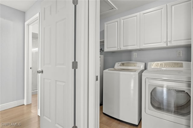 laundry room featuring separate washer and dryer, cabinets, and light hardwood / wood-style floors