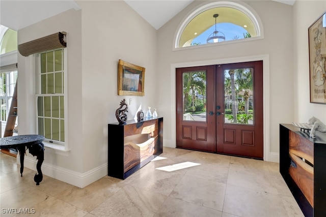 foyer featuring french doors, high vaulted ceiling, and light tile patterned floors