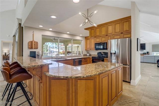 kitchen featuring a breakfast bar area, light stone counters, black appliances, and vaulted ceiling