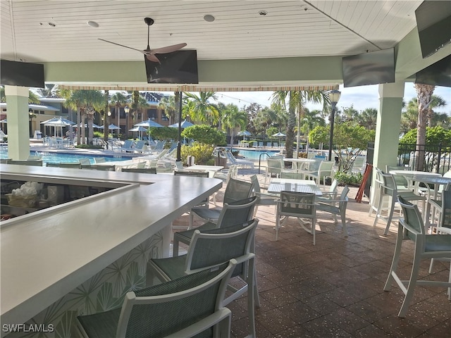 view of patio featuring ceiling fan, exterior bar, and a community pool