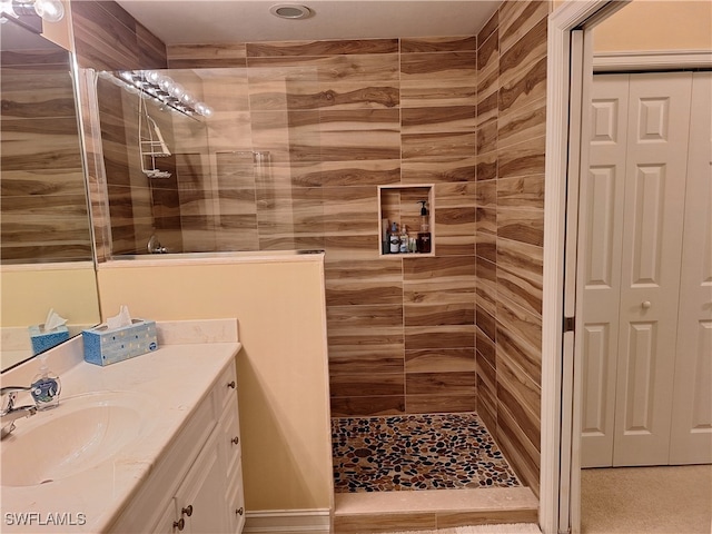 bathroom with a tile shower and vanity