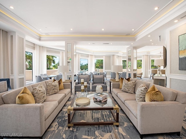 living room with a tray ceiling, crown molding, and a healthy amount of sunlight