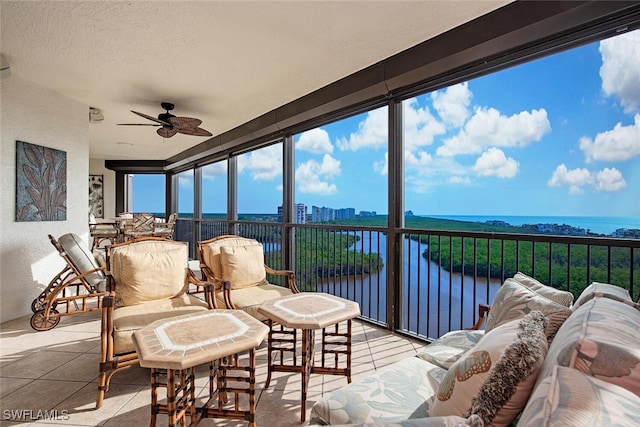 sunroom / solarium with ceiling fan and a water view