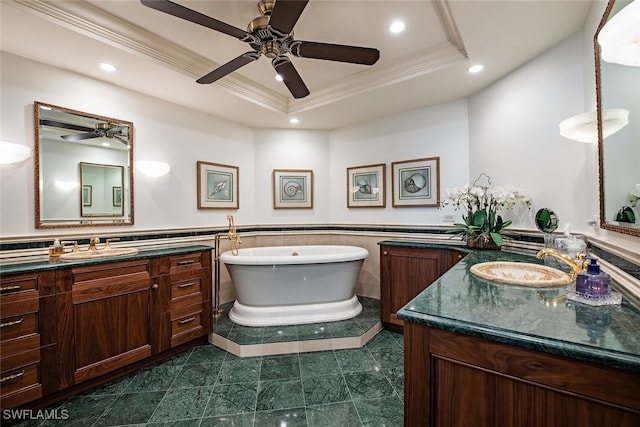 bathroom with a raised ceiling, a tub to relax in, vanity, and tile walls