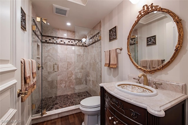 bathroom featuring hardwood / wood-style floors, toilet, a shower with door, vanity, and ornamental molding