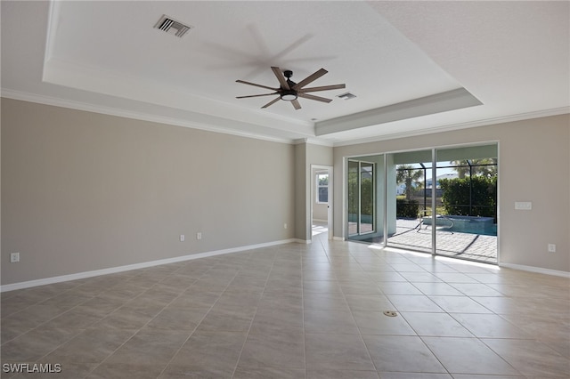 tiled spare room featuring a tray ceiling, ceiling fan, and ornamental molding