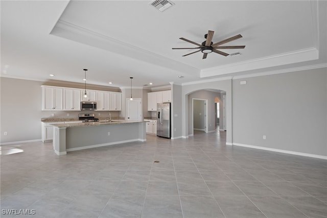 kitchen with white cabinets, stainless steel appliances, a raised ceiling, and a kitchen island with sink