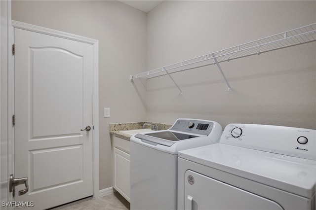 washroom featuring sink, cabinets, and independent washer and dryer