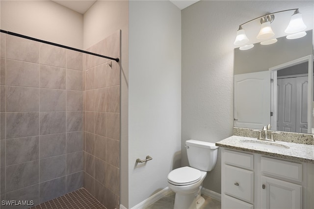 bathroom with a tile shower, vanity, and toilet