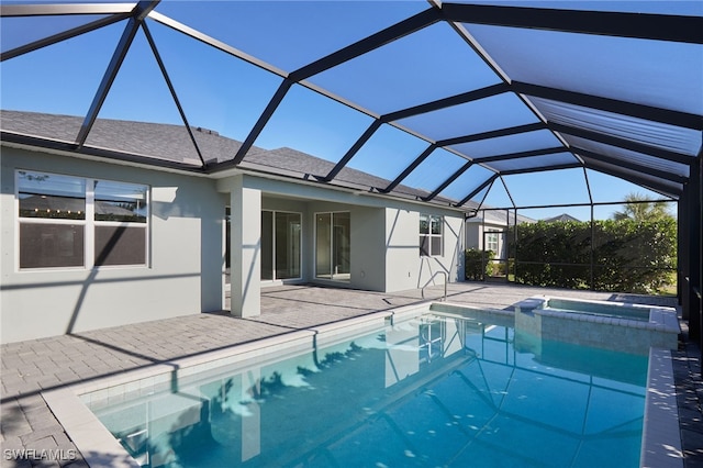 view of pool with glass enclosure, an in ground hot tub, and a patio