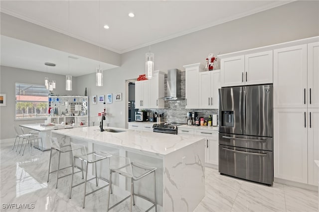 kitchen with white cabinetry, an island with sink, stainless steel appliances, and wall chimney range hood