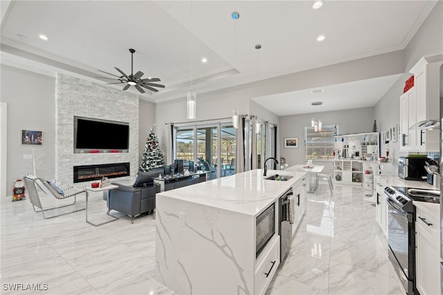 kitchen featuring appliances with stainless steel finishes, decorative light fixtures, white cabinetry, and a kitchen island with sink