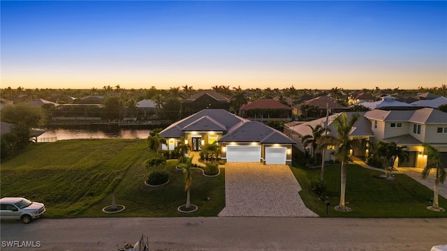 view of front of property with a lawn, a garage, and a water view