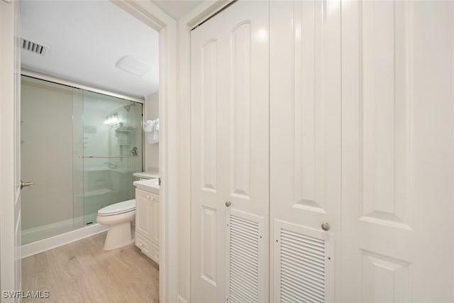 bathroom featuring hardwood / wood-style floors, vanity, toilet, and a shower with shower door