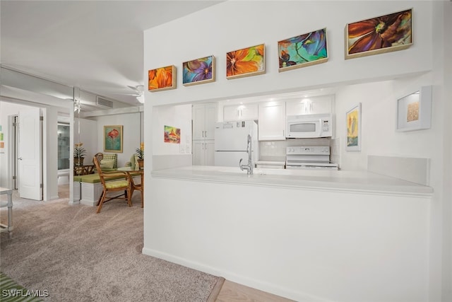 kitchen with kitchen peninsula, white cabinetry, white appliances, and light carpet