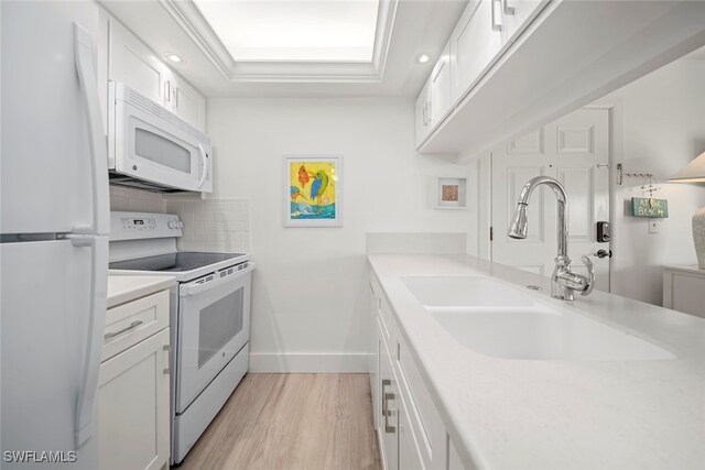 kitchen featuring backsplash, white appliances, sink, light hardwood / wood-style flooring, and white cabinetry