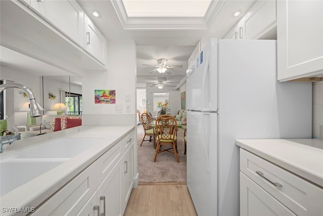 kitchen with white cabinets, sink, ceiling fan, light wood-type flooring, and white fridge