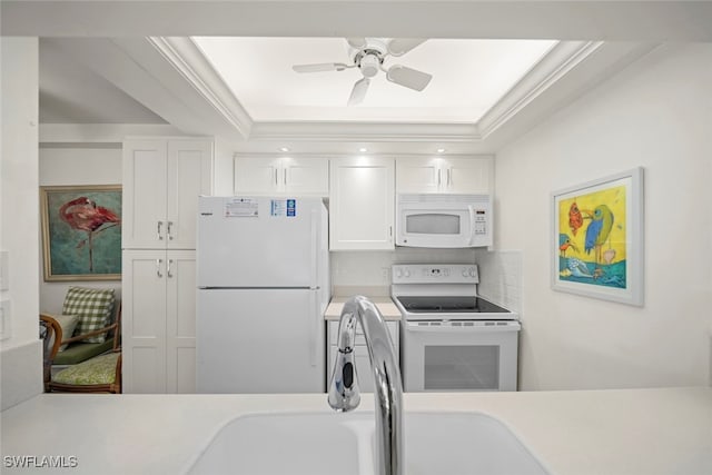 kitchen with white appliances, crown molding, ceiling fan, a tray ceiling, and white cabinetry