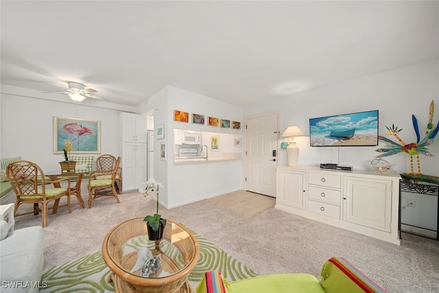 living room with light carpet, ceiling fan, and sink