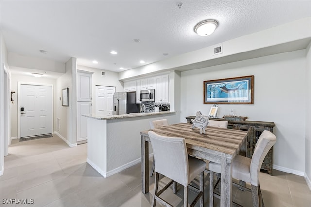 tiled dining area featuring a textured ceiling