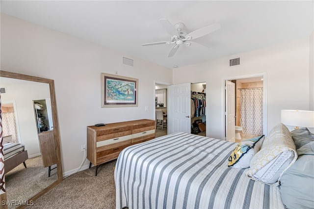 bedroom featuring ensuite bath, ceiling fan, a walk in closet, light carpet, and a closet