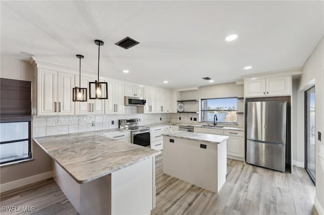 kitchen featuring light stone countertops, hanging light fixtures, a center island, stainless steel appliances, and white cabinets