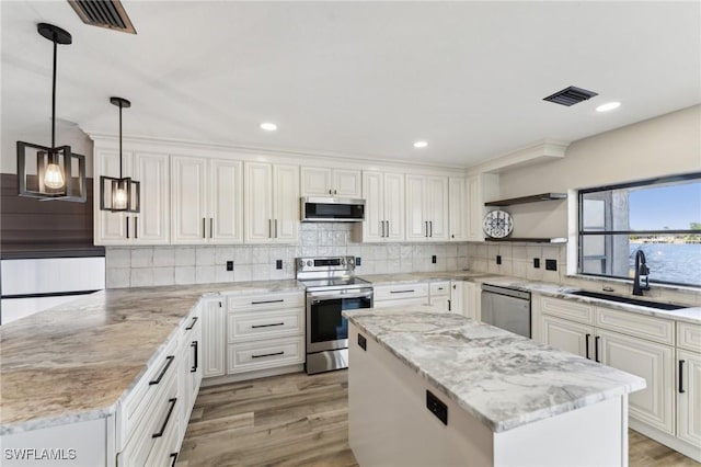 kitchen with sink, a center island, white cabinetry, pendant lighting, and appliances with stainless steel finishes