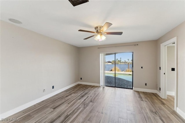 unfurnished room with ceiling fan, a water view, and light hardwood / wood-style flooring