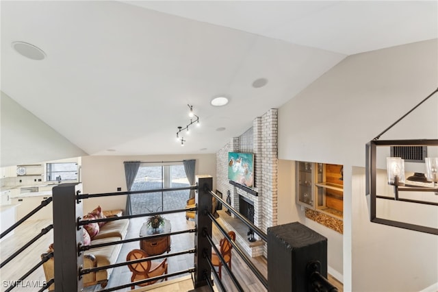 living room featuring a brick fireplace and vaulted ceiling