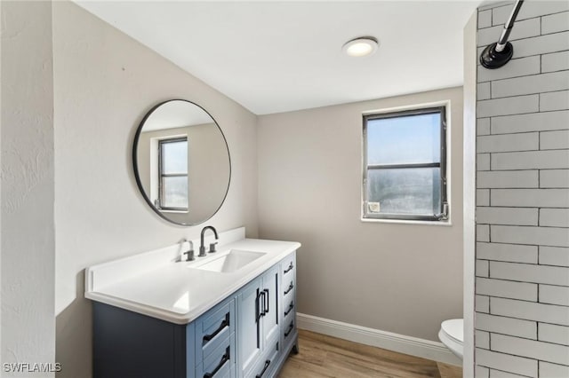 bathroom featuring toilet, vanity, hardwood / wood-style flooring, and plenty of natural light