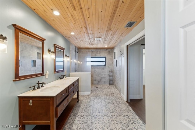 bathroom featuring wood ceiling, a tile shower, and vanity