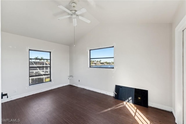 unfurnished room featuring ceiling fan, dark hardwood / wood-style floors, plenty of natural light, and a fireplace