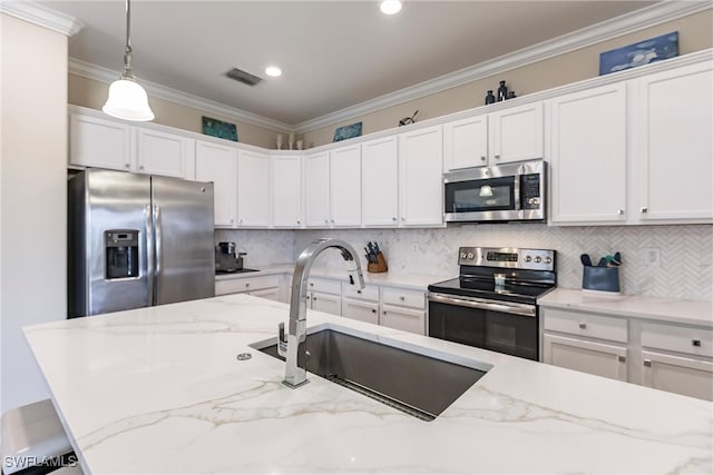 kitchen featuring appliances with stainless steel finishes, light stone counters, sink, white cabinetry, and hanging light fixtures