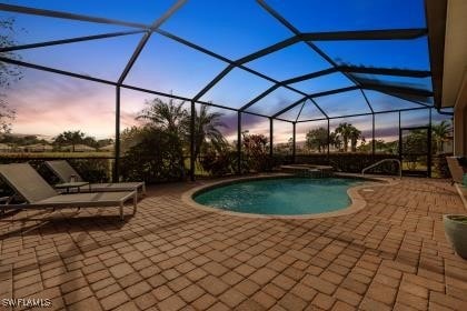 pool at dusk with a lanai, a patio, and an in ground hot tub