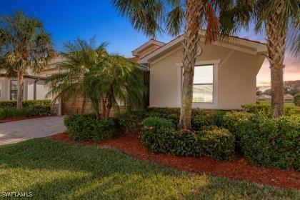 property exterior at dusk with decorative driveway, a yard, an attached garage, and stucco siding