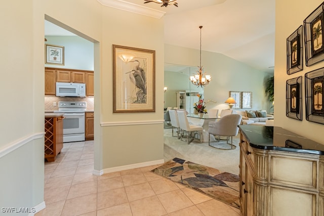 tiled dining space with lofted ceiling, ornamental molding, and an inviting chandelier