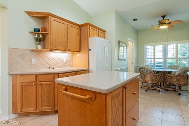 kitchen featuring a center island, white fridge, light tile patterned floors, and backsplash