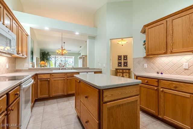 kitchen featuring pendant lighting, white appliances, an inviting chandelier, sink, and a kitchen island