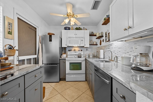 kitchen featuring white cabinets, appliances with stainless steel finishes, light stone counters, and sink